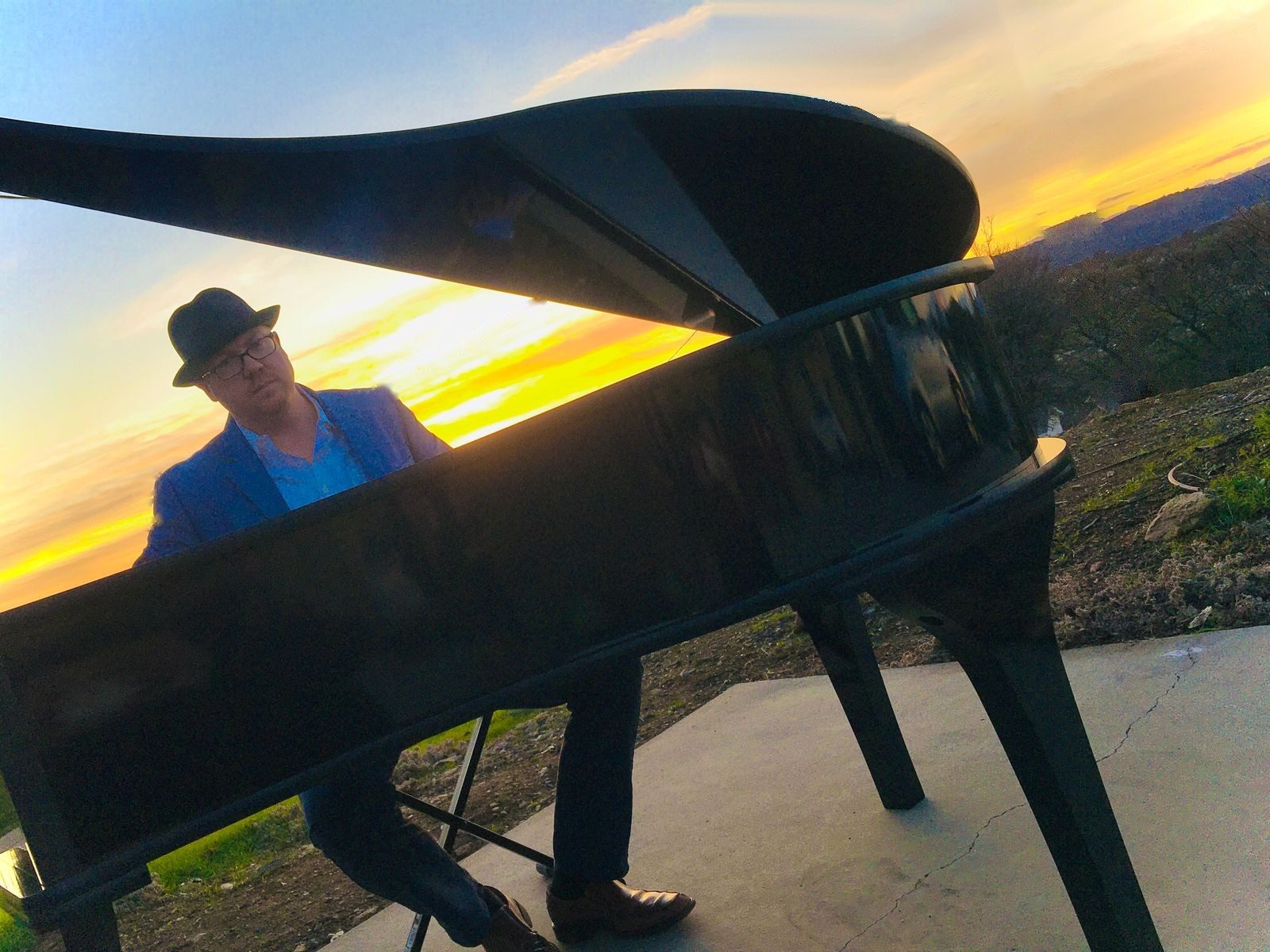 James Michael Day playing a grand piano outdoors at sunset